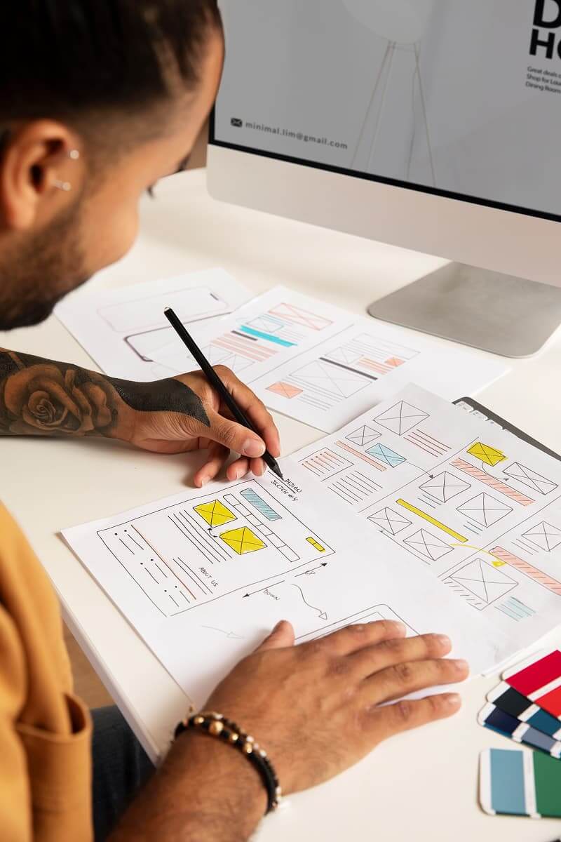 Person sketching website UI layouts by hand during the early web design planning process